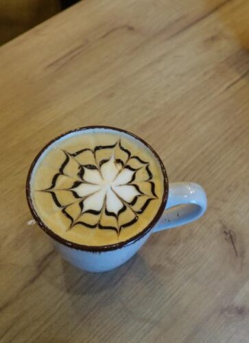 Na zdjęciu klientka kuszona pięknie udekorowanym latte art.